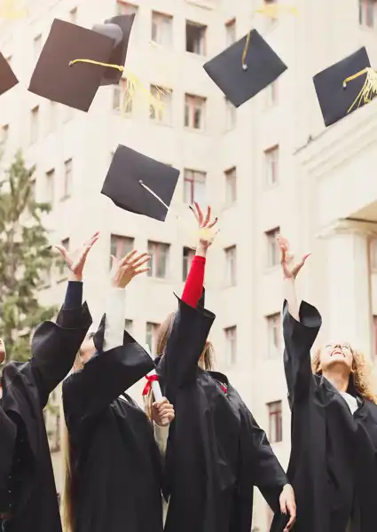 A group of people in black graduation gowns throwing their graduation caps