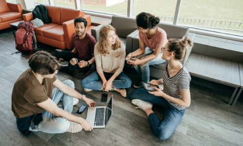 Students sitting on the floor in a hotel common area, chatting and socializing