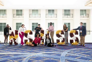 A group of students standing next to NSHSS Balloon letters