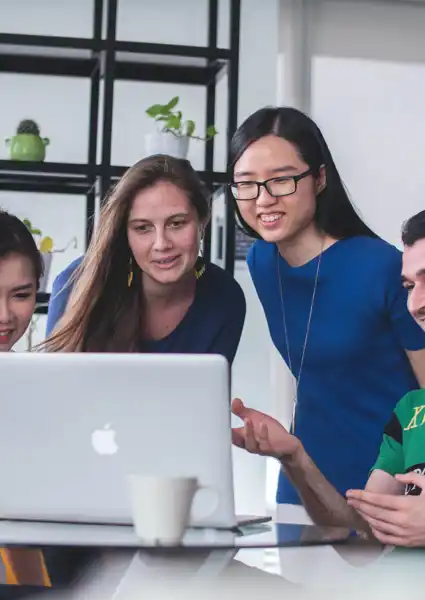 Four Students looking at a mac laptop smiling