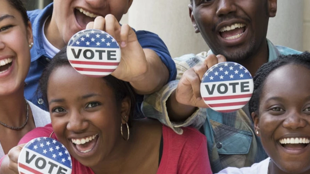 A diverse group of people raising vote stickers
